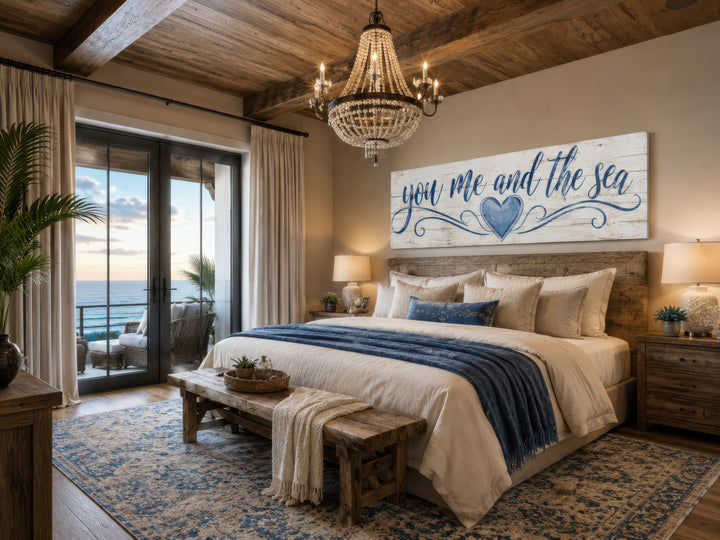 You Me And The Sea wall art in navy script on white wood above a bed in a coastal master bedroom.