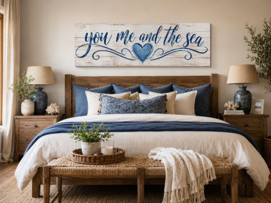You Me And The Sea wall art above a bed with blue and white coastal decor in a master bedroom.