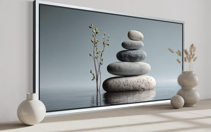Zen stacked stones horizontal grey minimalist wall art in a silver frame on a neutral wall.