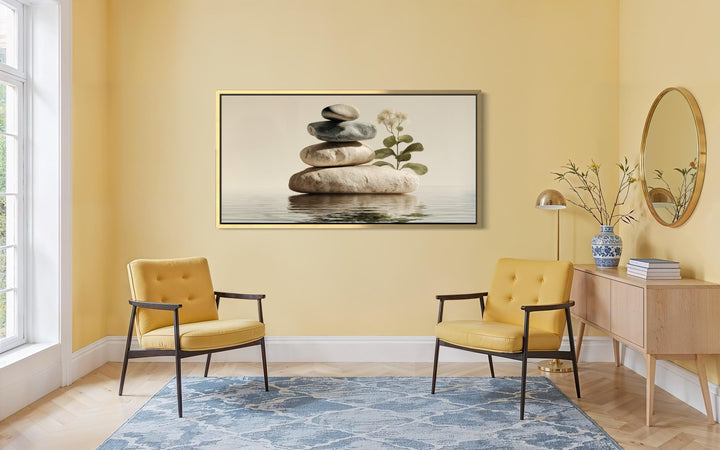 Horizontal wall art of stacked stones and a botanical sprig in a warm, minimalist room.