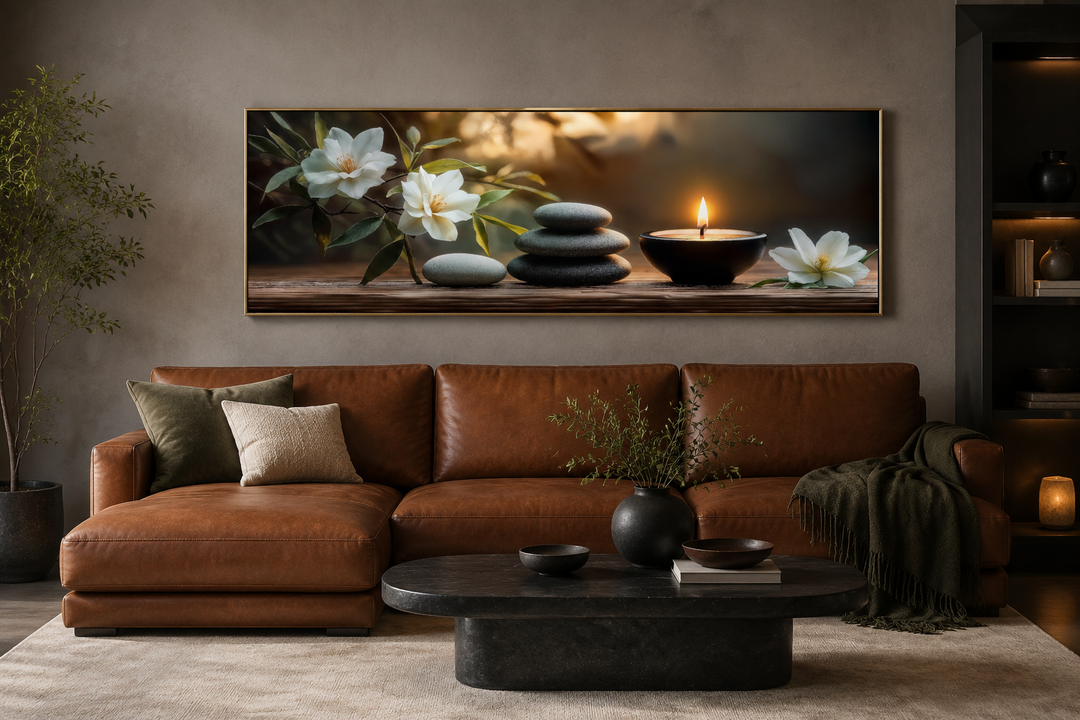 Zen stones, candle, and magnolia flowers long horizontal framed canvas wall art above a brown sofa.