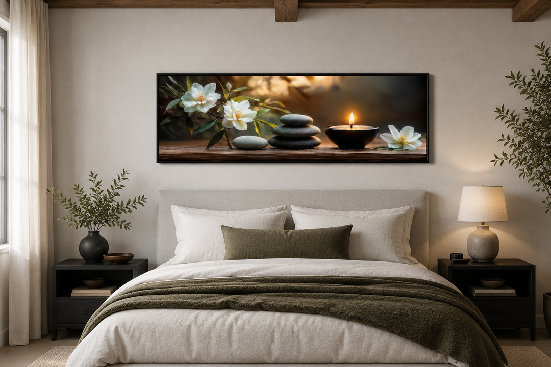 Zen stones, candle, and magnolia flowers on a long horizontal framed canvas above a bed.