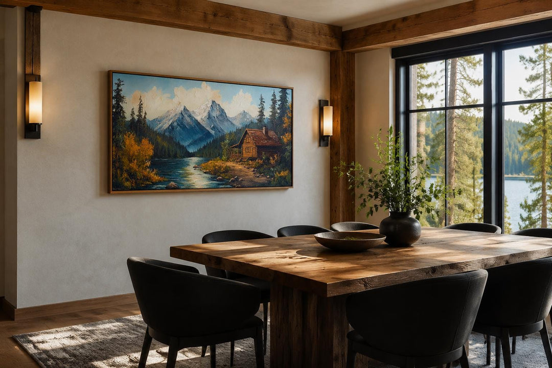 Vintage style canvas wall art of a mountain cabin by a river in a rustic dining room setting.