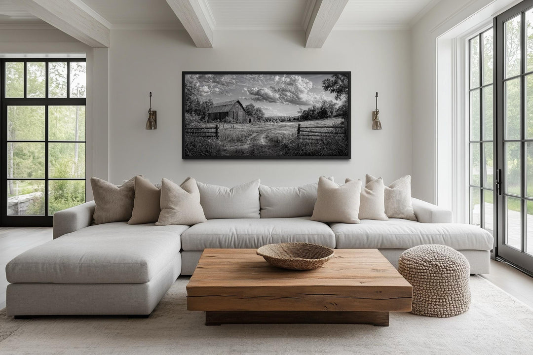 Black and white barn landscape canvas wall art hanging above a neutral sofa in a rustic living room.