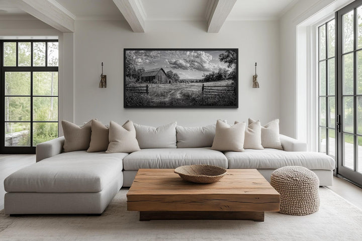 Black and white barn landscape canvas wall art hanging above a neutral sofa in a rustic living room.