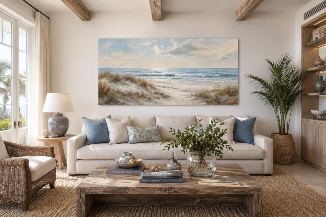 Wide horizontal wall art of sandy beach dunes, sea grass, and rolling waves in a coastal living room.