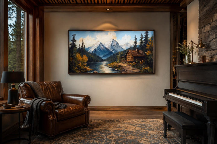 Vintage style canvas wall art of a mountain cabin by a river in a rustic living room setting.