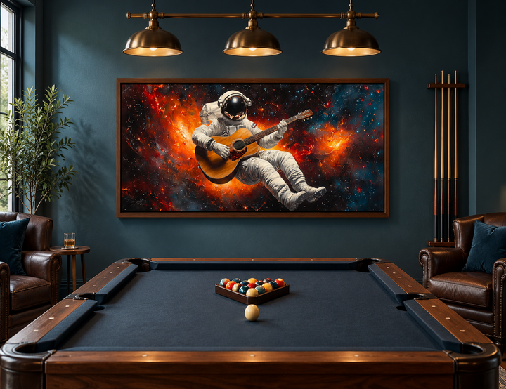 Astronaut playing guitar framed canvas wall art above a pool table in a dark blue room.