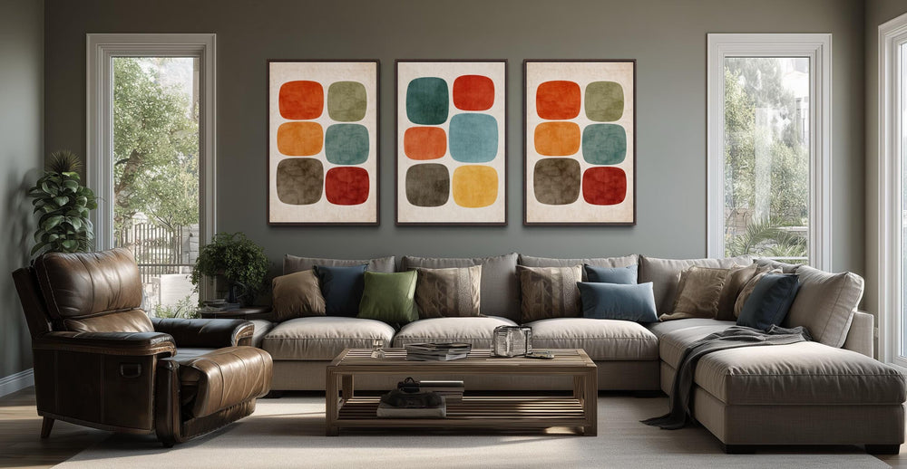 Set of 3 mid-century modern canvas prints with earth tone geometric shapes above a grey sofa.