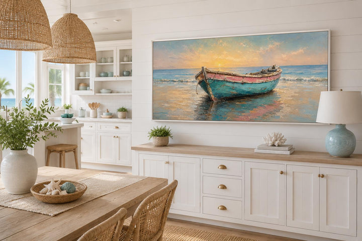 Weathered teal and pink rowboat on a beach at golden sunset, framed coastal wall art in a room.