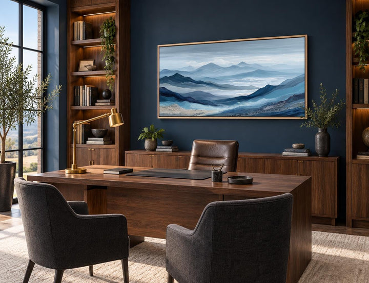 Blue mountain landscape canvas wall art with misty peaks in a horizontal frame above a wooden desk.