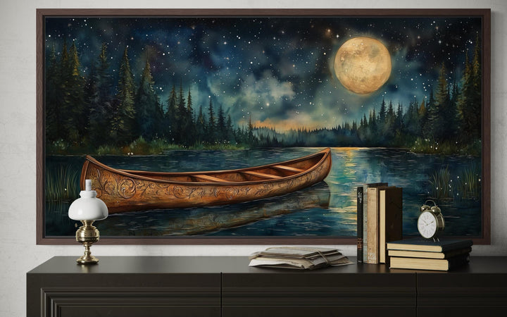 Canoe on moonlit lake and forest night scene canvas wall art displayed above a dark wood dresser.