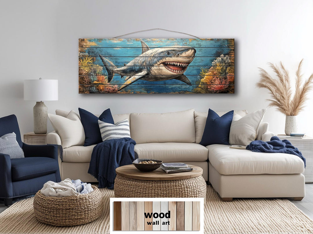 Horizontal wood wall art of a great white shark in a coral reef hanging above a modern sofa.