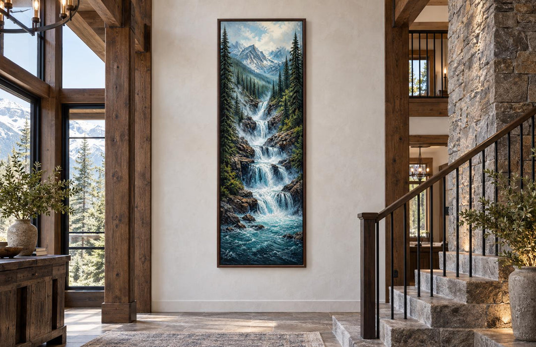 Tall narrow canvas art of a cascading waterfall through a pine forest with snow-capped peaks.