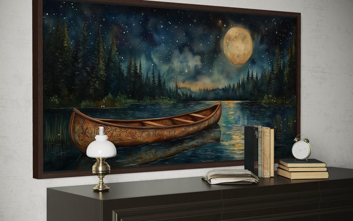 Canoe on moonlit lake and forest night scene canvas wall art displayed above a dark wood dresser.