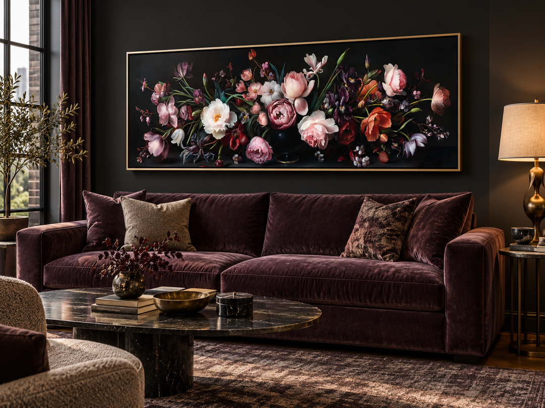 Panoramic wall art of moody dark flowers in a gold frame above a velvet couch.