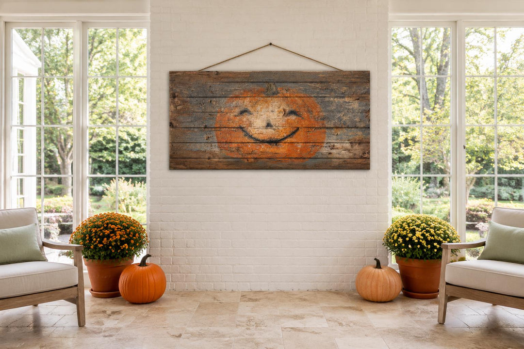 Primitive pumpkin face on distressed wood planks with a rope hanger in a farmhouse living room.