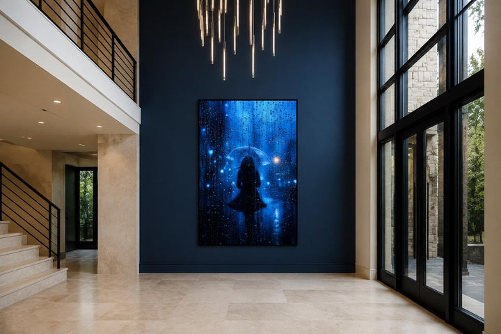 Vertical canvas art of a woman's silhouette with an umbrella in blue rain on a navy wall.