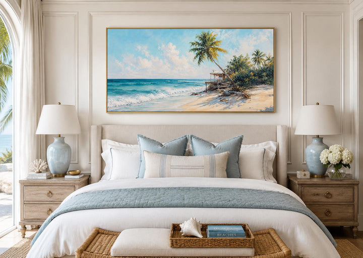 Tropical beach wall art with palm trees and turquoise waves above a bed in a coastal bedroom.
