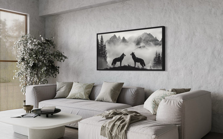 Two Wolves On the Cliff In Foggy Mountains Black White Framed Canvas Wall Art in a living room with a couch and a coffee table