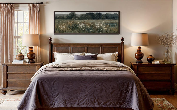A long, narrow horizontal painting of a moody wildflower field hangs above a dark wood bed.