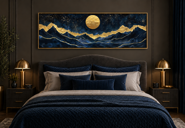 Panoramic gold and navy canvas print of a moonlit mountain landscape above a modern bed.
