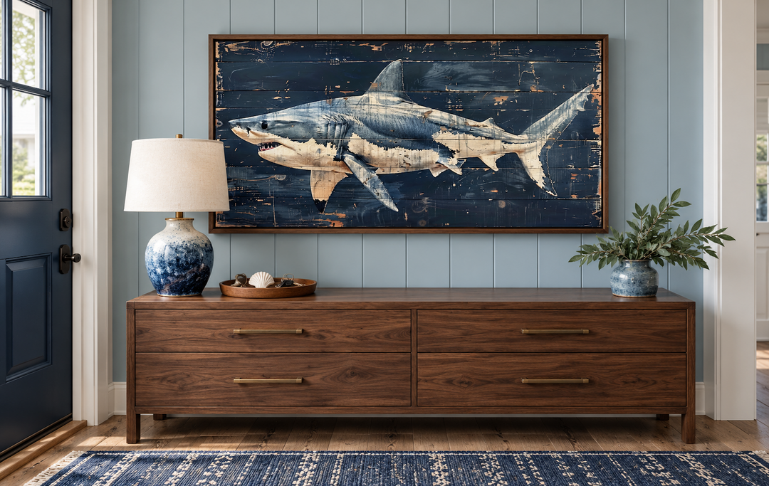 Great white shark painting on navy blue distressed wood frame above a walnut console table.