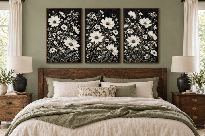 Set of 3 white wildflower canvas prints on black backgrounds above a rustic wooden bed frame.