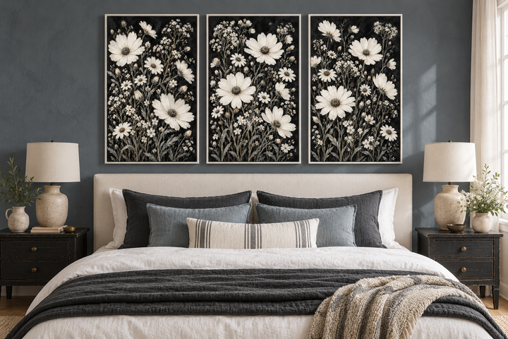 Set of 3 white wildflower canvas prints on a black background above a neutral upholstered bed.