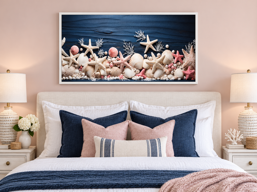 Coastal wall art of pink starfish and seashells on navy blue wood above a bed with matching pillows.