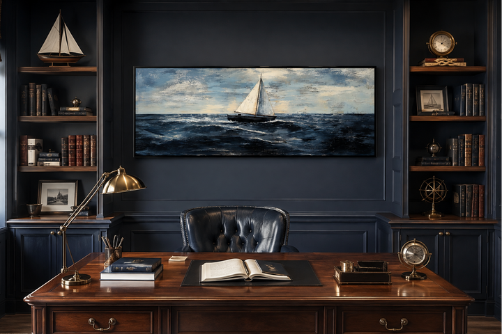 Long horizontal canvas art of a sailboat on a dark ocean, hung in a classic navy blue home office.