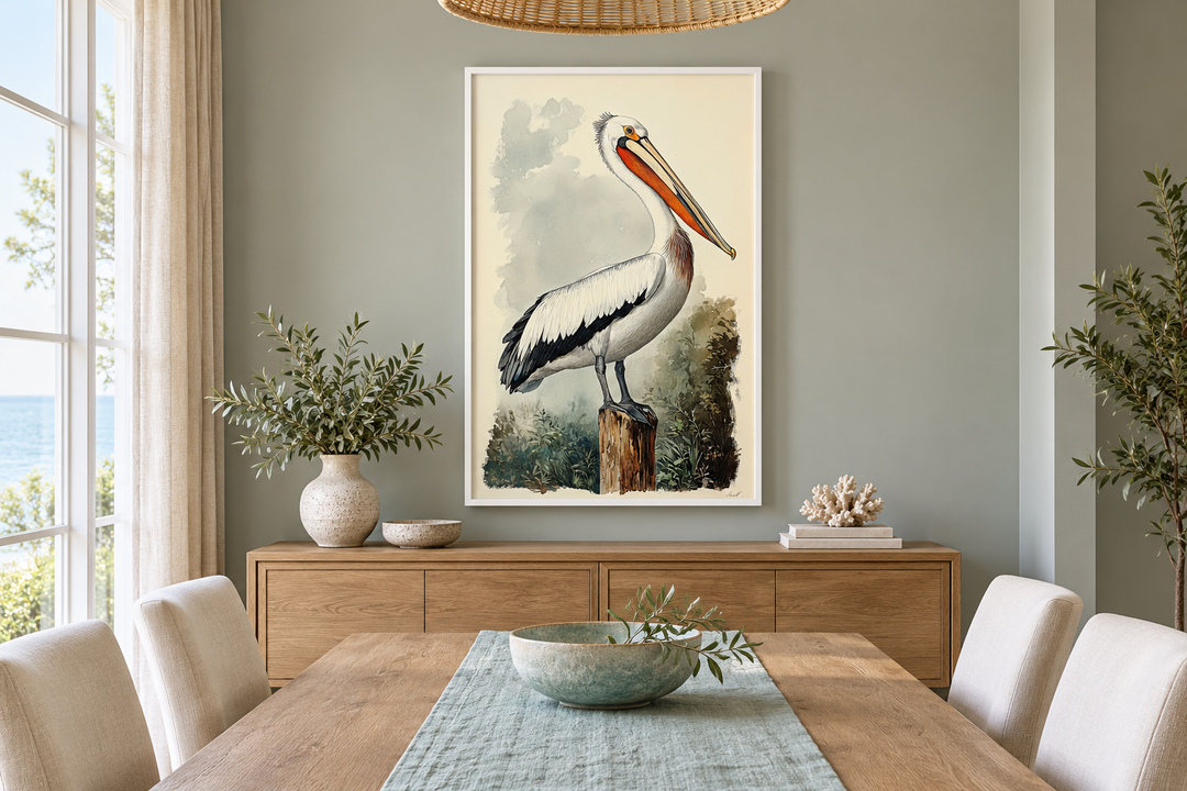Vintage pelican illustration in a white frame hanging above a wooden sideboard in a dining room.
