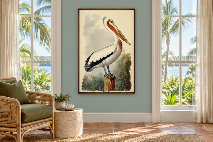 Vintage pelican illustration in a walnut frame, hanging in a coastal sunroom with a rattan chair.