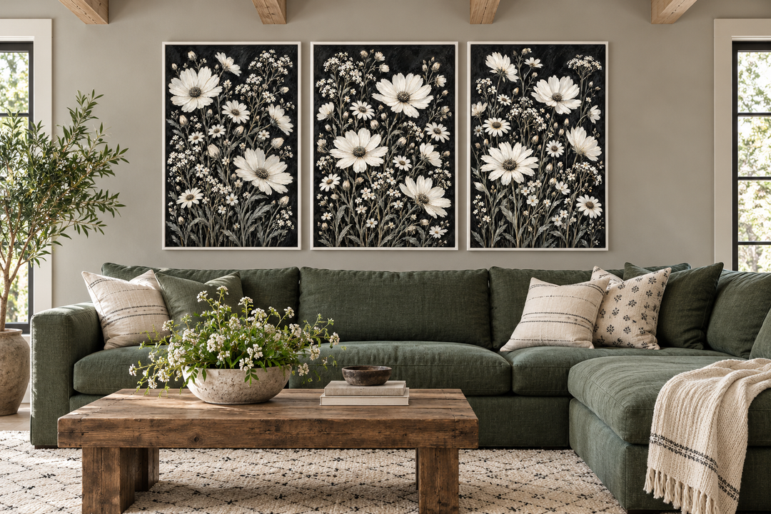 Set of 3 white wildflower canvas prints on black backgrounds above a green sectional sofa.